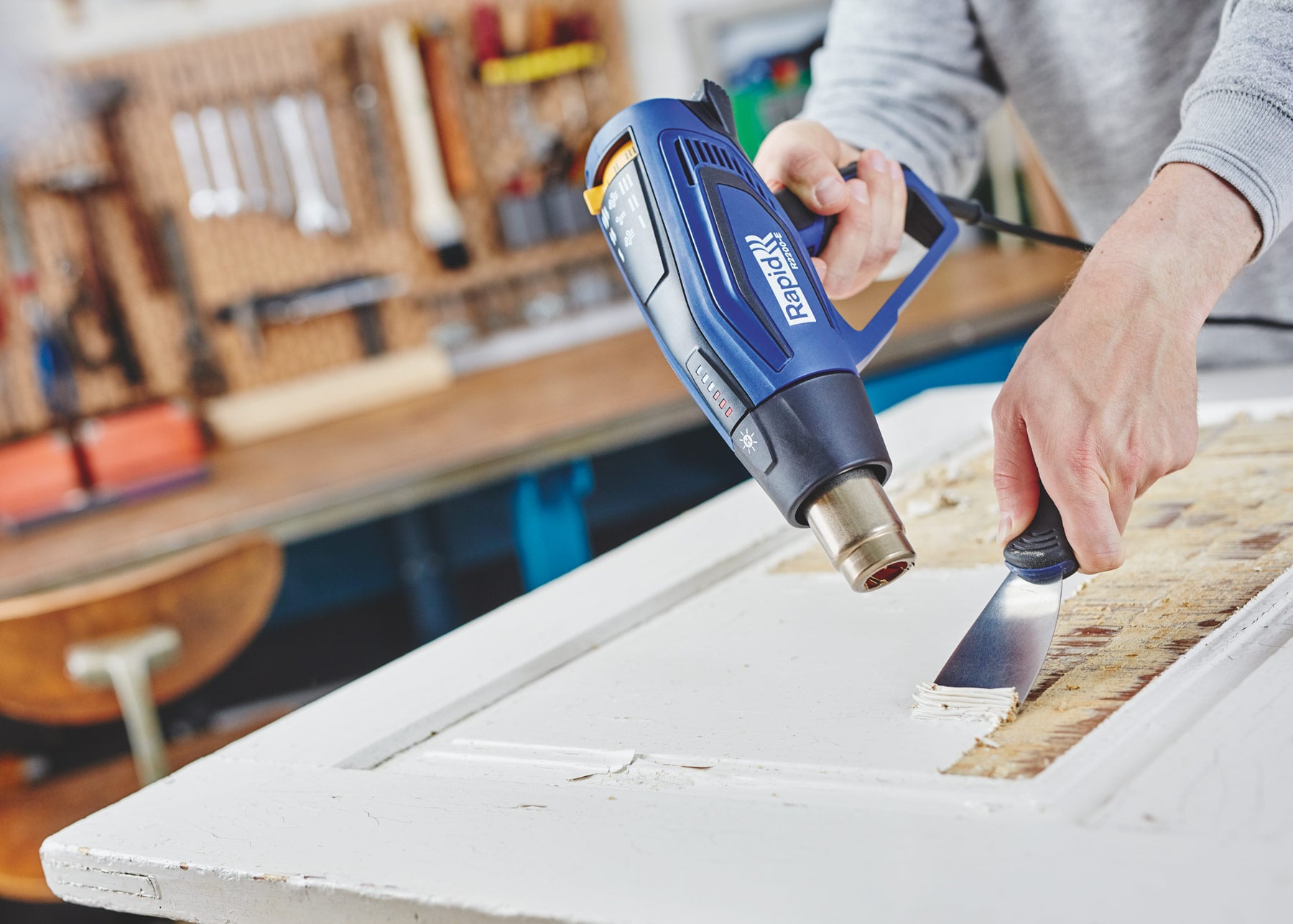 Hot air gun removing paint from a window frame